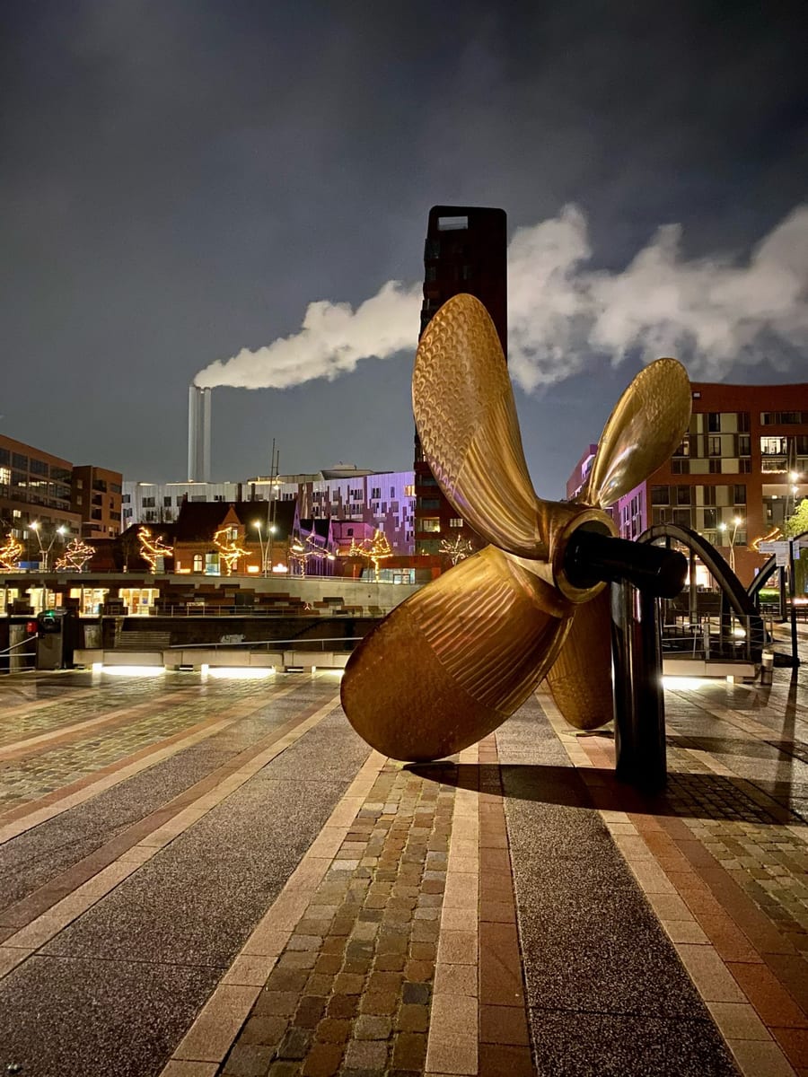A golden ship propeller sculpture in Hamburg at night.